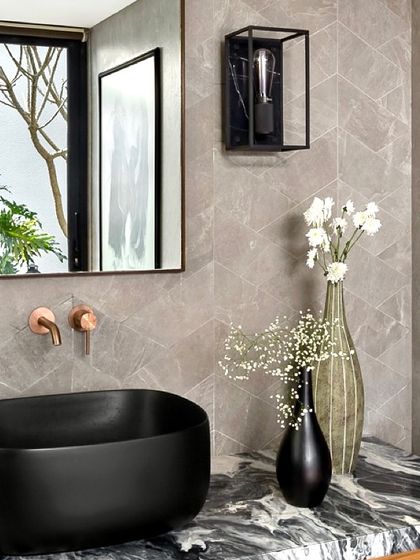 A close-up of the black vessel sink and copper-finish taps in the Mango Orchard House bathroom. The combination of different materials and finishes adds a rich, tactile quality.