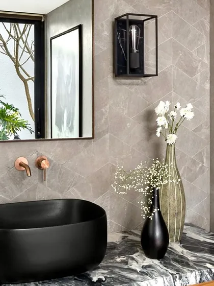 A close-up detail of the bathroom vanity, highlighting the contrast between the organic patterns of the marble, the smooth black sink, and the geometric tiles on the wall.