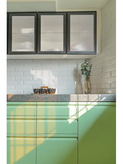A close-up on the fluted glass overhead cabinets and the subway tile backsplash. These textural details add depth and character to the minimalist design.