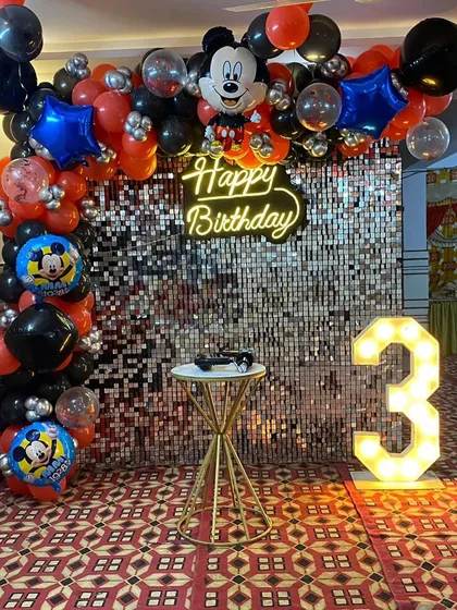 Another angle of the Mickey Mouse party decor, highlighting the balloon arrangement and neon 'Happy Birthday' sign.