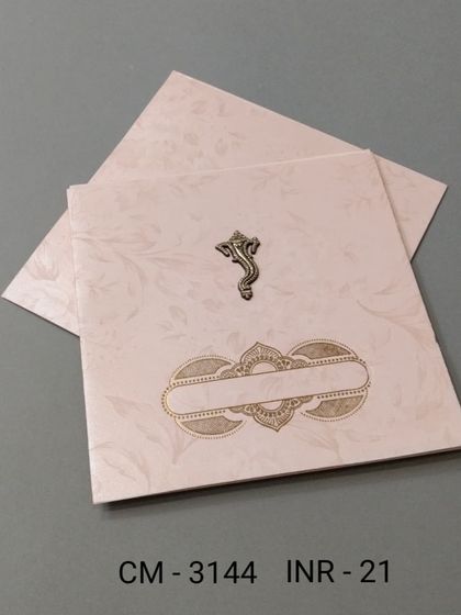 A classic square wedding card in a subtle cream color. It features a metallic Ganesha emblem on the front and provides a simple, elegant space for your invitation.