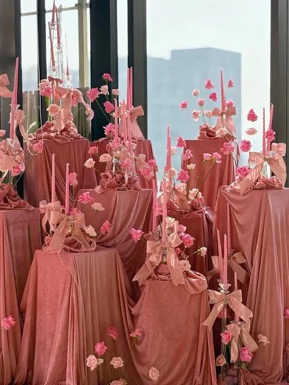The full view of our multi-level velvet installation, where each pedestal holds a unique arrangement of candles, flowers, and ribbons. This creates a dynamic and visually rich focal point in the room.