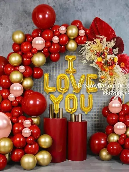 A very grand and stylish 'I LOVE YOU' balloon arrangement. This setup is perfect for proposals or engagements, using a mix of red and gold balloons with pedestals and dried floral accents.