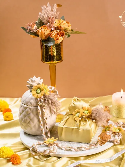 This Diwali hamper is a blend of rustic charm and festive elegance. It features a decorative vase, a ceramic jar, and a satin potli, all beautifully arranged on a marble-finish tray.