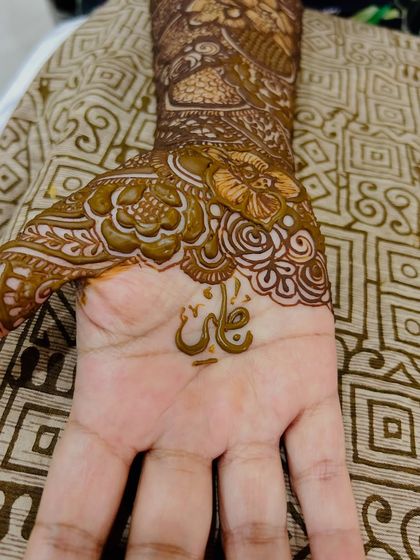 A close-up of the palm, showing the groom's name "Ali" written in a beautiful floral frame.