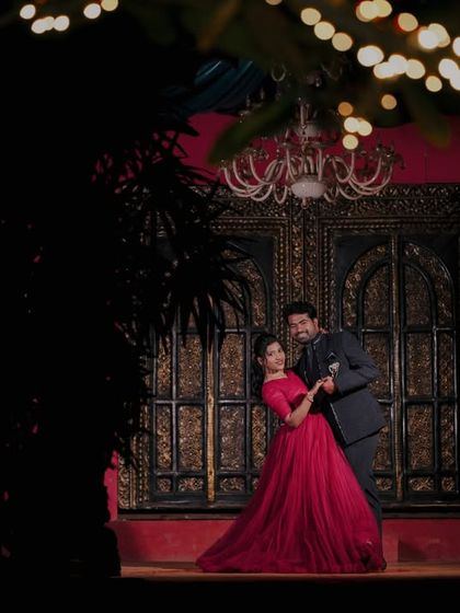 A dramatic shot with a bokeh foreground, focusing on the couple dancing in front of an ornate, warmly lit doorway.