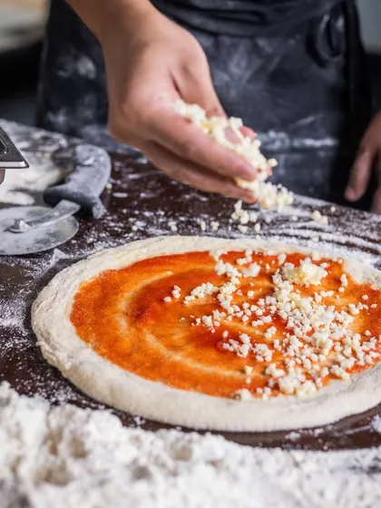 Too much cheese? There's no such thing. A generous handful of cheese is sprinkled over the pizza base.