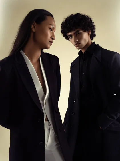 A powerful duo shot for a power-suiting brand. The image showcases both men's and women's tailoring, creating a modern, androgynous, and sophisticated mood.
