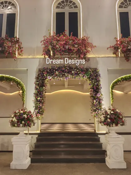 A symmetrical and elegant entrance setup. The central floral arch is flanked by two smaller arches and large floral urns, creating a balanced and picture-perfect welcome.