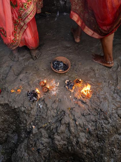 The remnants of offerings and diyas on the muddy banks of the river after a Chhath Puja ritual, a beautiful trace of the devotion that took place.