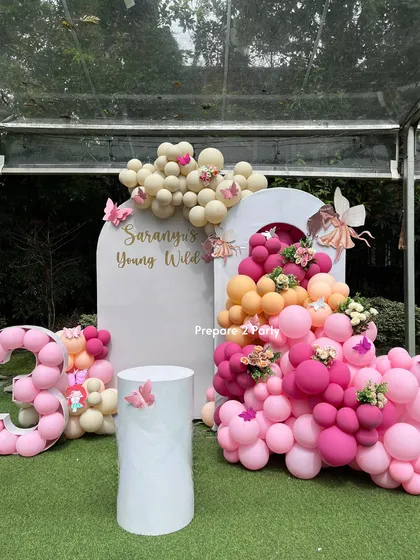 For this 'Young, Wild & 30' birthday, we created a whimsical fairy and butterfly theme. The setup includes a personalized arched backdrop, a vibrant balloon cascade in pinks and oranges, and a custom balloon number display.