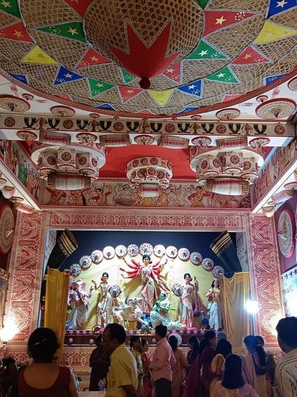 The beautifully decorated interior of the Durga Puja pandal, showcasing the idols against a backdrop of Assamese cultural art.