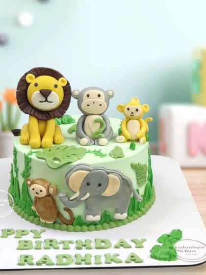 An Animal Kingdom cake with cute, friendly fondant animals like a lion, monkey, and elephant on a soft green base.