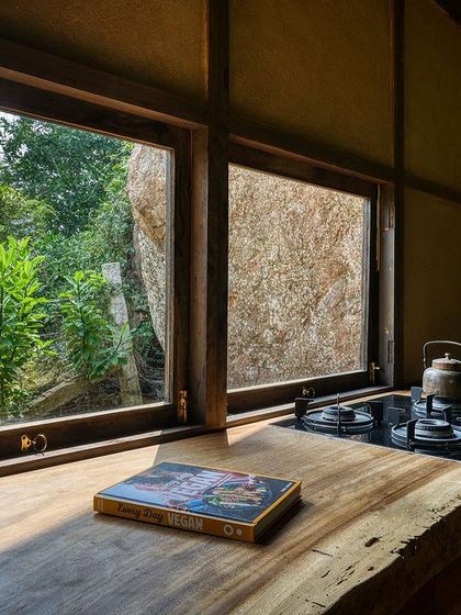 The kitchen counter, with its live-edge wood and large windows, is a beautiful and functional space for preparing meals while surrounded by nature.