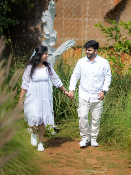 A happy, walking shot of a couple holding hands in a rustic, outdoor section of the studio, showcasing the variety of natural backdrops available.