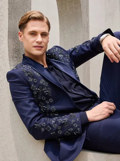 A relaxed portrait in the statement navy tuxedo, giving a clear view of the detailed embroidery and the satin shawl collar. This is understated luxury that makes you stand taller.