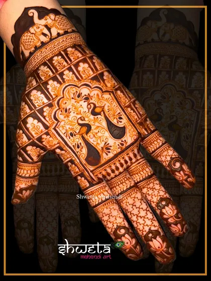 This intricate hand design features majestic peacocks within an ornate arch. The surrounding grid pattern and elephant motifs on the wristband add to its traditional charm.