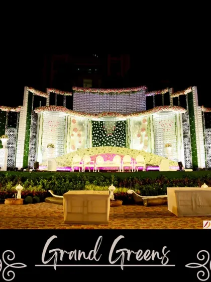 A full view of the "Grand Greens" stage, showcasing its impressive scale. The design combines architectural elements with walls of greenery and flowers, creating a look of structured, natural opulence.