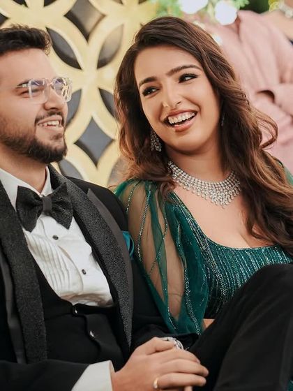 The happy couple, Pragya and Akhil, enjoying their reception. The elegant backdrop with gold geometric patterns and lush greenery was designed to create a sophisticated and warm ambiance.