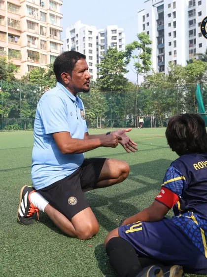 A coach kneels down to speak with a player at eye level during a break in a match. This personal approach ensures that instructions are clear and encouraging.