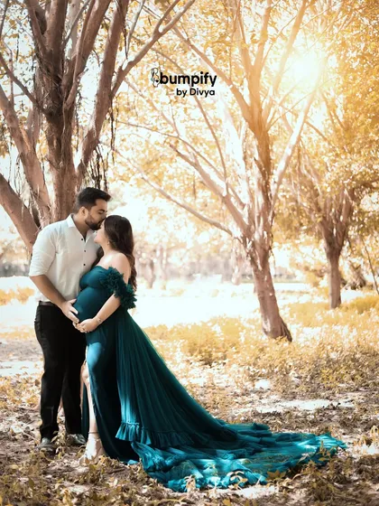 A tender kiss shared between the couple during their golden hour outdoor shoot. The warm sunlight filtering through the trees creates a dreamy and romantic atmosphere.