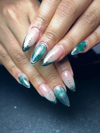 An elegant design with a deep green cat eye effect on almond-shaped nails, accented with delicate silver stars and dots.