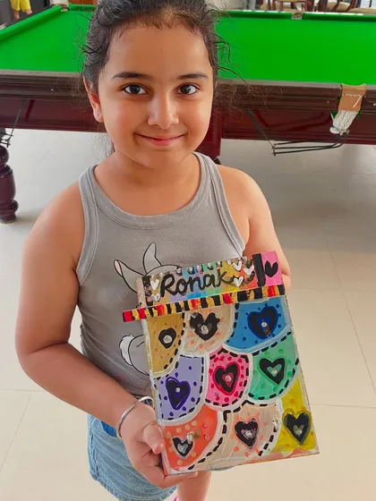 A proud artist with her colorful, heart-filled creation for her dad, Ronak.