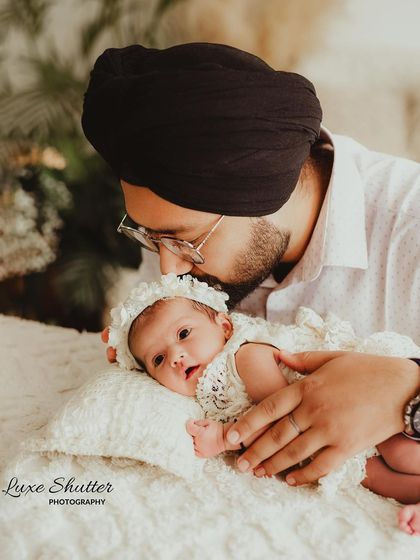 A father's gentle affection for his newborn daughter, a beautiful portrait that includes cultural attire like the turban.
