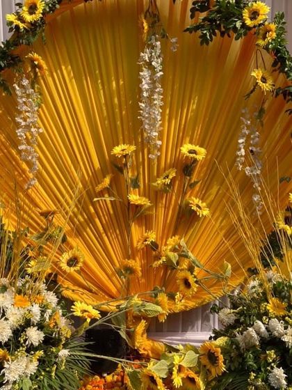 A stunning backdrop of yellow drapes and sunflowers for a Haldi ceremony. This setup provides a perfect, vibrant background for photos and makes the entire space feel festive.