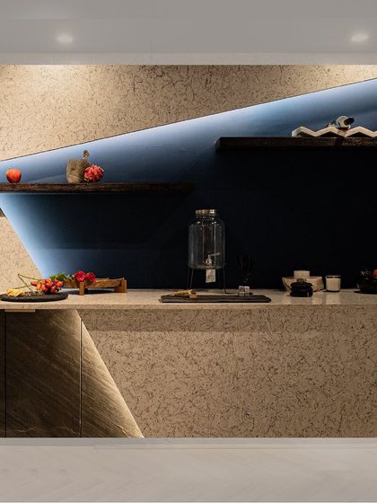 A straight-on view of the bar counter, emphasizing the clean lines and material interplay. The diagonal cut in the stone facade, highlighted by an LED strip, adds a dynamic and modern touch to the design.