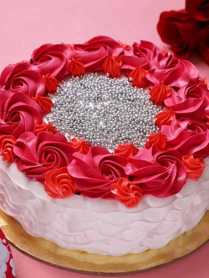 This beautiful cake is decorated with a ring of red and pink buttercream rosettes and filled with sparkling silver sugar pearls. It's a glamorous and festive option for birthdays and special celebrations.