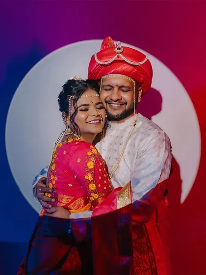 A creative couple portrait using bold red and blue lighting to create a modern, artistic feel while still honoring the traditional Maharashtrian wedding look.