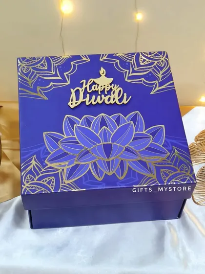The lid of our signature blue lotus box. The intricate gold foil design and the 'Happy Diwali' cutout make the packaging just as special as the gifts inside.