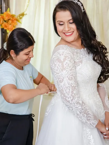 A behind-the-scenes shot of the gown being fitted. The bride's joyful expression shows the excitement of the final moments before the ceremony.