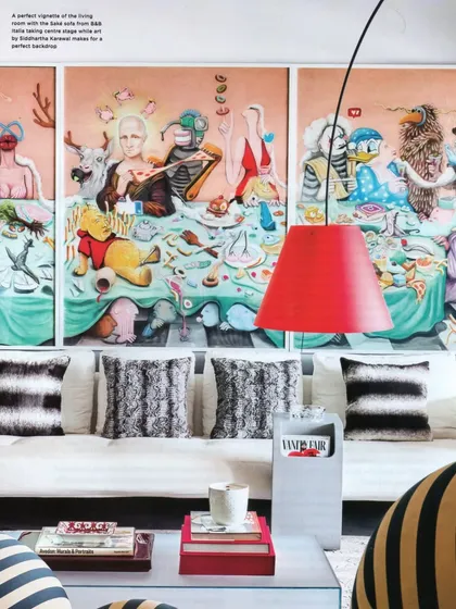 A close-up of the living room from the Livingetc feature. The massive, surreal artwork serves as a stunning backdrop for the eclectic mix of modern and classic furniture.