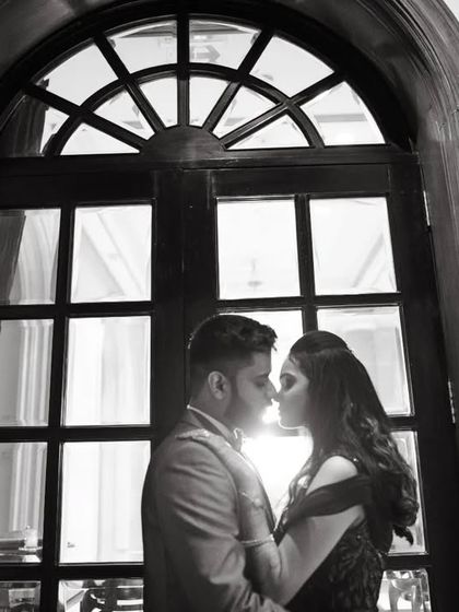A silhouette of a couple about to kiss, framed by a large window. This dramatic black and white shot is both romantic and artistic.