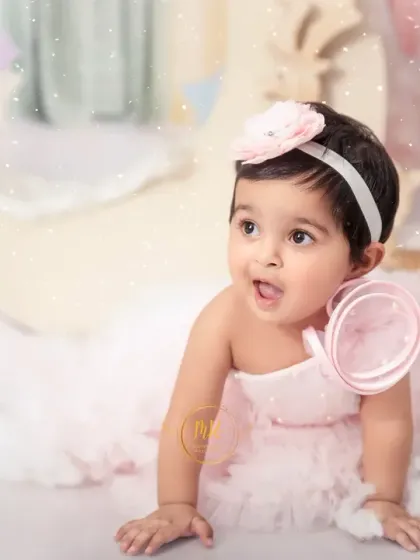 An expressive shot of a baby girl looking up with wonder during her dreamy, cloud-themed first birthday session.