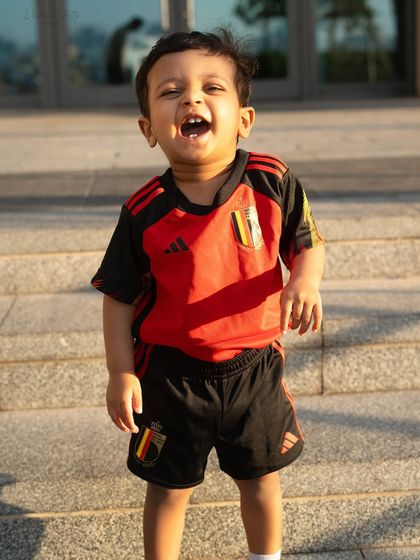 A little football fan enjoying the sunshine. Outdoor sessions are great for capturing toddlers' energy and playful spirit.