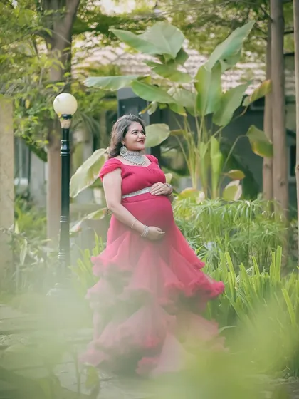 An outdoor maternity shoot set in a lush garden, featuring a vibrant pink ruffled gown. Natural settings like this provide a beautiful, serene backdrop for your pregnancy portraits.