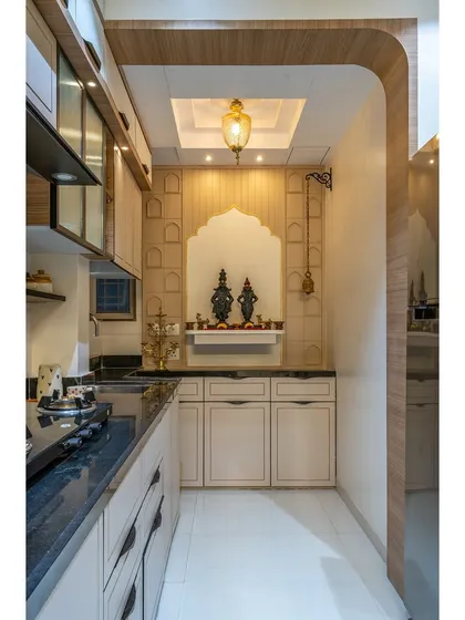 A wider view of the kitchen puja mandir, showing how it is framed by a custom archway and illuminated by a dedicated pendant light.