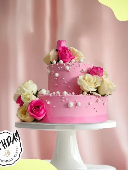 A beautiful two-tier pink floral cake. The layers of pink frosting and fresh roses create a stunning centerpiece for a birthday or anniversary.