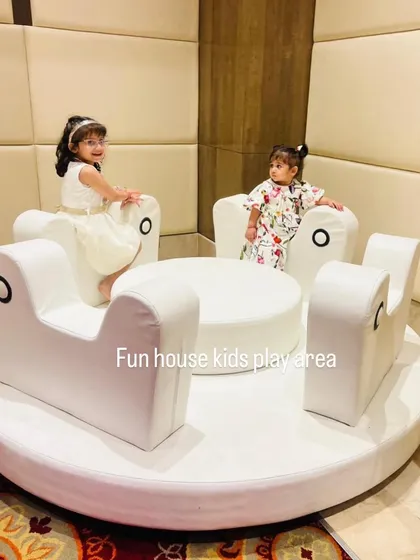 Two young girls seated on the plush, comfortable seats of the white merry-go-round.