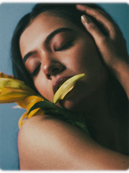 An intimate and sensory portrait, with a single petal resting on the model's lips. It's a shot that evokes the sense of touch and smell, adding a deeper layer to the floral beauty story.
