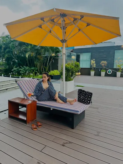 The full view of my spot by the pool. The striped co-ord set looks chic against the yellow umbrella and blue water.