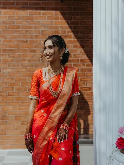 A beautiful, sunlit portrait of the bride-to-be on her engagement day, dressed in a stunning orange saree.