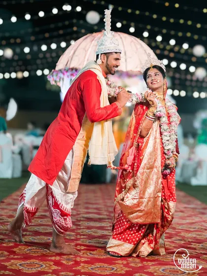 A playful interaction between the bride and groom during their Bengali wedding.