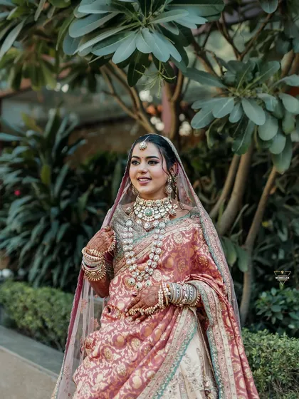 A portrait of the bride in a unique pastel-colored saree-lehenga, her elegance shining in a garden setting.
