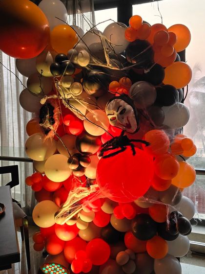 A Halloween-themed balloon installation. I used orange, black, and white balloons mixed with spiderwebs and spooky masks to create a fun and festive photo backdrop.