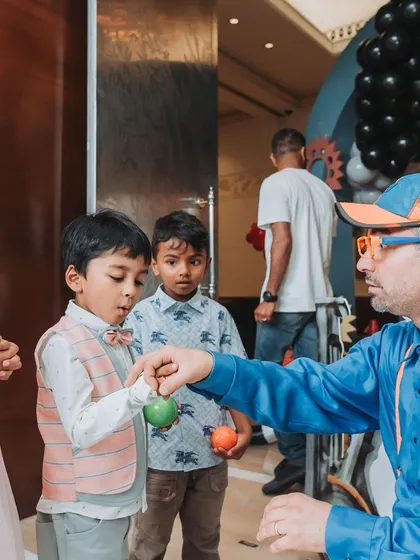 An entertainer dressed as a construction worker performs magic tricks for the children, keeping them captivated and amazed.