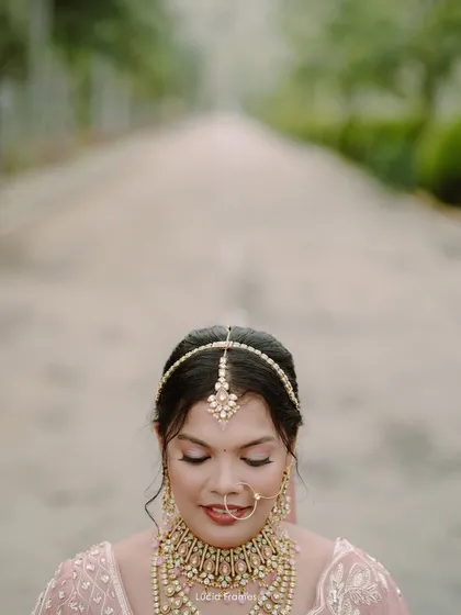A serene close-up of the bride with her eyes closed, showcasing her intricate matha patti and flawless makeup.